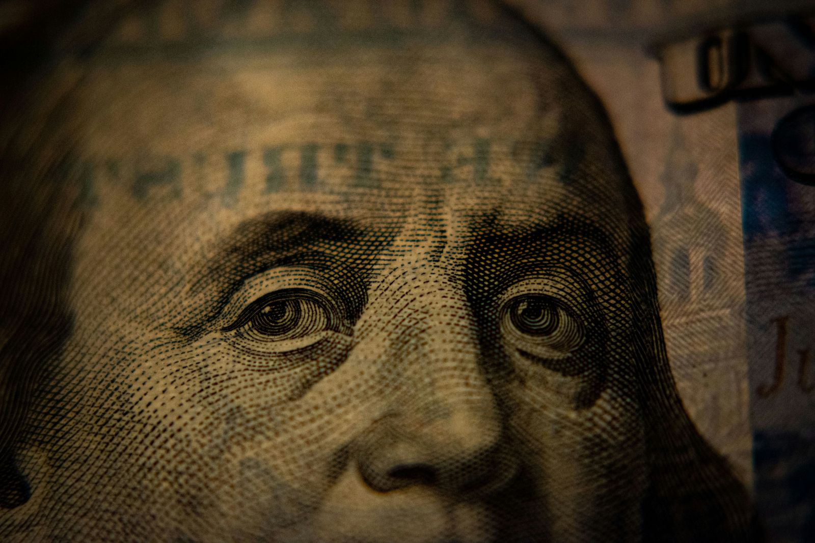 Close-up photograph of Benjamin Franklin’s portrait engraved on a US hundred-dollar bill.