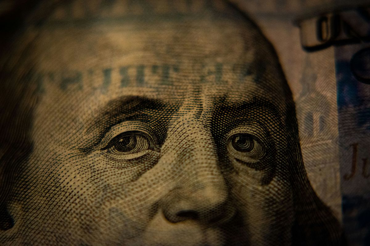 Close-up photograph of Benjamin Franklin’s portrait engraved on a US hundred-dollar bill.
